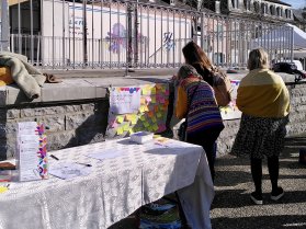 Des personnes vues de dos devant des affiches sur une place de Mauléon