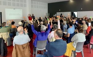 Assemblée générale où des personnes assises lèvent la main pour voter