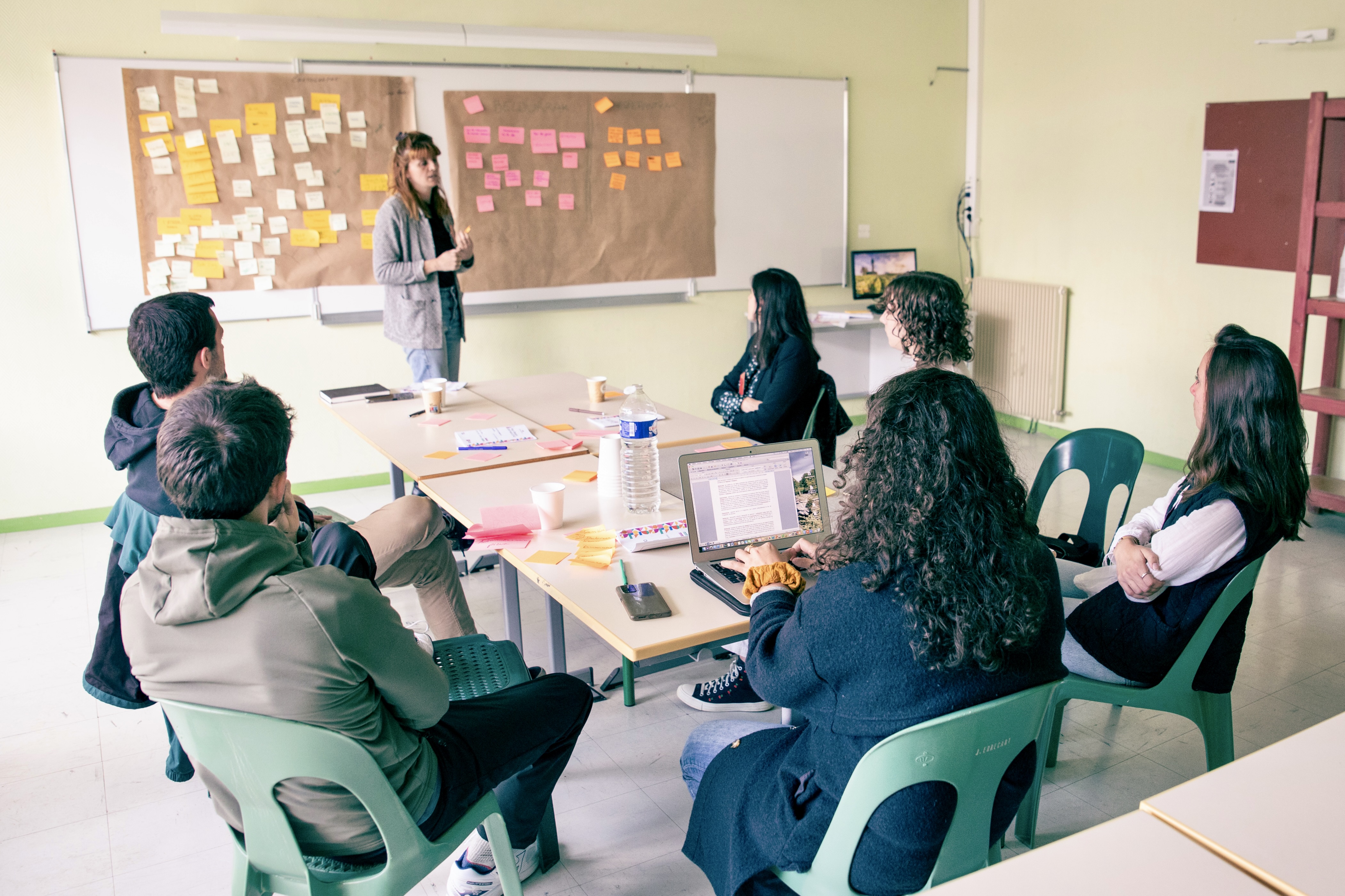 Atelier avec six participants et une animatrice devant un tableau blanc sur lequel sont collés des posts its